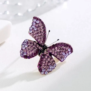 Sparkling butterfly brooch with purple rhinestones on a minimalist white background