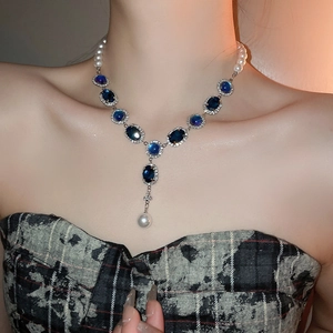 Collier de style français avec pierre bleue ovale et perle blanche porté par modèle