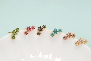 Close-up of colorful floral stud earrings with micro-set zircons on ceramic edge