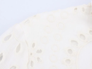 Macro shot of white cotton dress showing intricate floral embroidery and eyelet details