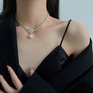 Detailed view of pearl drop necklace with heart-shaped rhinestone on a model neck
