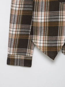 Détail des poignets et de l'ourlet asymétrique de la chemise à carreaux tissée