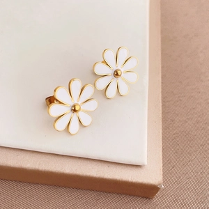 Macro detail of white enamel daisy earrings with gold center and polished metallic edges