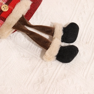 Close-up of Christmas stocking detail featuring plaid fabric, wooden button, and felt boots