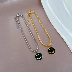Nahaufnahme von gold- und silberfarbenen Perlenarmbändern mit Smiley-Anhängern auf Stoff