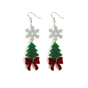 Detailed view of Christmas earrings with glittery snowflakes, green trees, and red bows