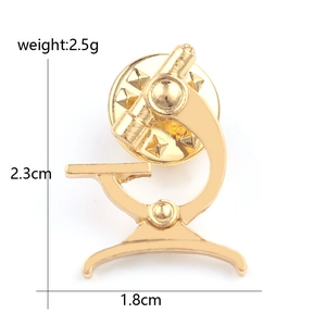 Detailed close-up of a gold microscope enamel pin with size and weight measurements