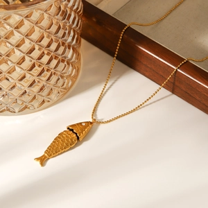 Detailed view of an 18k gold fish pendant necklace with sparkling stone inlay