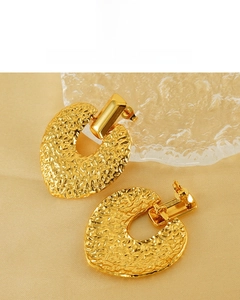 Détails macro de boucles d'oreilles cœur plaqué or 18K avec texture martelée sur soie