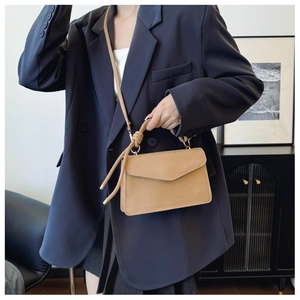 Detail of light brown suede crossbody bag featuring a unique knotted handle and gold metal hardware