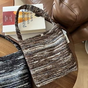 Detail of tweed shoulder bag featuring a woven texture and silver magnetic snap closure
