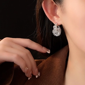 Close-up of model wearing twisted silver hollow C-shaped earrings in polished metal