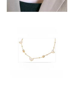 Detailed macro view of gold plated titanium necklace with white shell heart and zircon charm