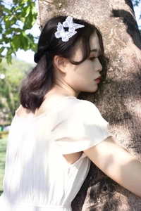 Close-up of white embroidered butterfly hair clips on model in a natural outdoor setting