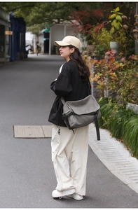 Outdoor shot of a man wearing a grey canvas messenger bag with adjustable buckle strap