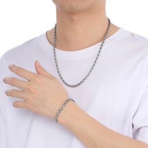 Détail d'un ensemble collier et bracelet en chaîne torsadée argentée sur un modèle en t-shirt