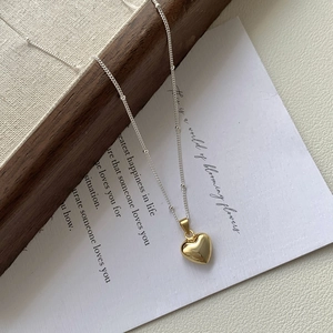 Detail of a 925 silver necklace featuring a 3D gold heart pendant and beaded chain links
