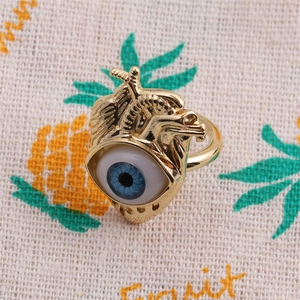 Macro detail of gold plated anatomical heart ring featuring a realistic blue eyeball inlay