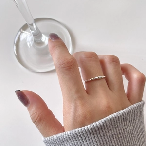 Close-up of minimalist silver ring with hammered texture and three green zircon stones