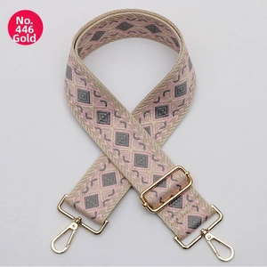 Detail of a pink and gray woven wide strap with gold metal lobster clasps and buckle