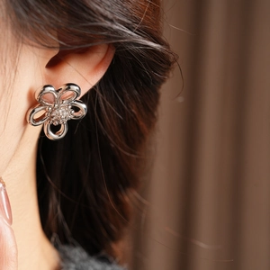 Detail view of a hollow flower stud earring with sparkling zircon on a model