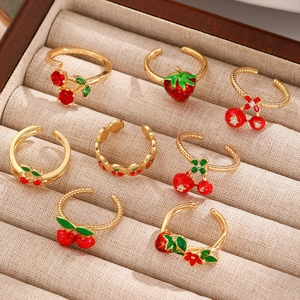 Detail of adjustable gold rings with enamel strawberry and cherry fruit charms with zircons