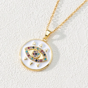 Macro detail of golden evil eye pendant with colorful zircon stones on white leather