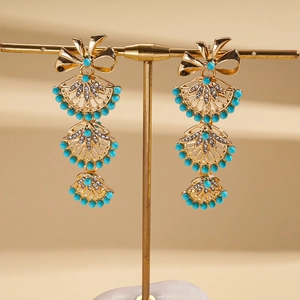 Detail of vintage gold fan bow earrings with turquoise beads and crystal pavé on a stand