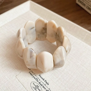 Detailed view of the creamy marble-patterned resin bracelet on a minimal tray