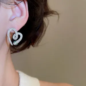 Silver snake heart earrings with white zircon pavé and green gem eyes on model