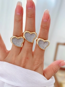 Detailed view of three gold-plated heart rings with pavé cubic zirconia on hand