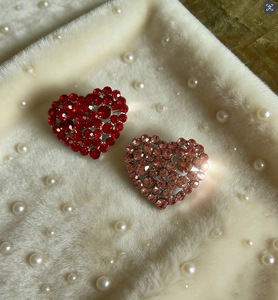 Close-up of red and pink heart brooches with pave-set rhinestones on soft faux fur