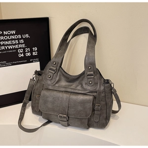 Close-up of gray faux leather tote bag showing front pocket and detachable shoulder strap