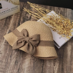 Flat lay of khaki straw hat with brown bow tie on vintage wood and dried flowers