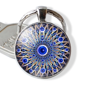Detail of the blue evil eye mandala pendant keychain with metallic ring on a white surface