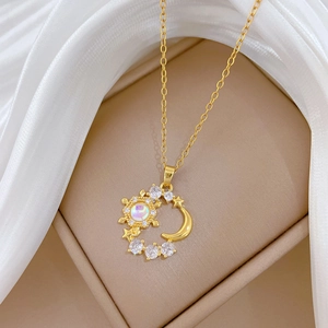 Luxurious gold moon and star pendant necklace with sparkling crystals on a beige stand