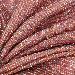 Close-up of pink and burgundy metallic knit fabric with glittery threads and high-density texture