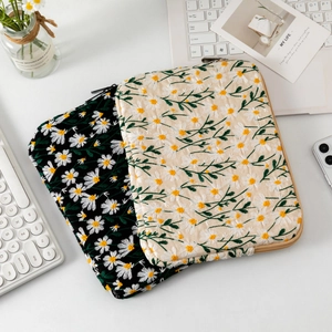 Detailed embroidery of daisy patterns on quilted laptop sleeves in black and beige