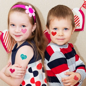 Colorful heart-shaped temporary tattoo stickers for children on festive face and body