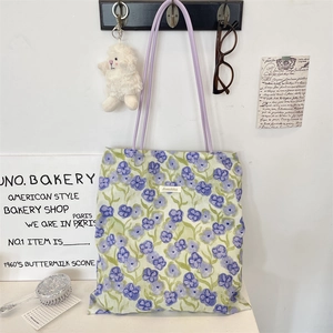 Dettaglio della borsa tote in tela floreale con spalline in pelle viola e logo Sorakka