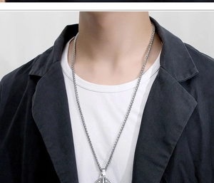 Close-up of silver compass pendant necklace worn over a black blazer and white t-shirt