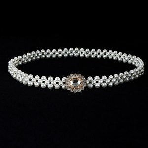 Close-up of white pearls waist belt with elegant gold and silver rhinestone buckles
