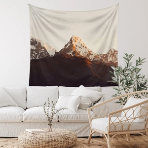 Detailed close-up of bohemian mountain sunset tapestry hanging above a white sofa