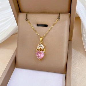 Detail of pink heart-shaped crystal necklace with crown design on beige silk fabric