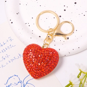 Detail of red heart crystal keychain with gold metal clasp on decorative porcelain plate