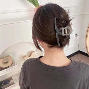 Minimalist matte grey-green shark hair claw clip for women styled in a chic hair bun