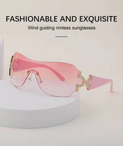 Pink gradient rimless Y2K sunglasses with rhinestone details on a white display stand