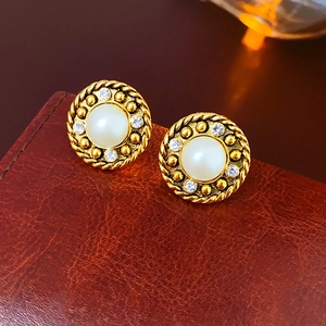 Détail de boucles d'oreilles perles vintage avec halo de strass sur cuir marron