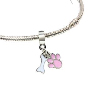 Detailed macro view of silver snake chain bracelet with white bone and pink paw pendants