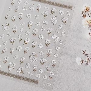 Detailed macro view of 3D embossed white camellia nail stickers with golden leaf accents